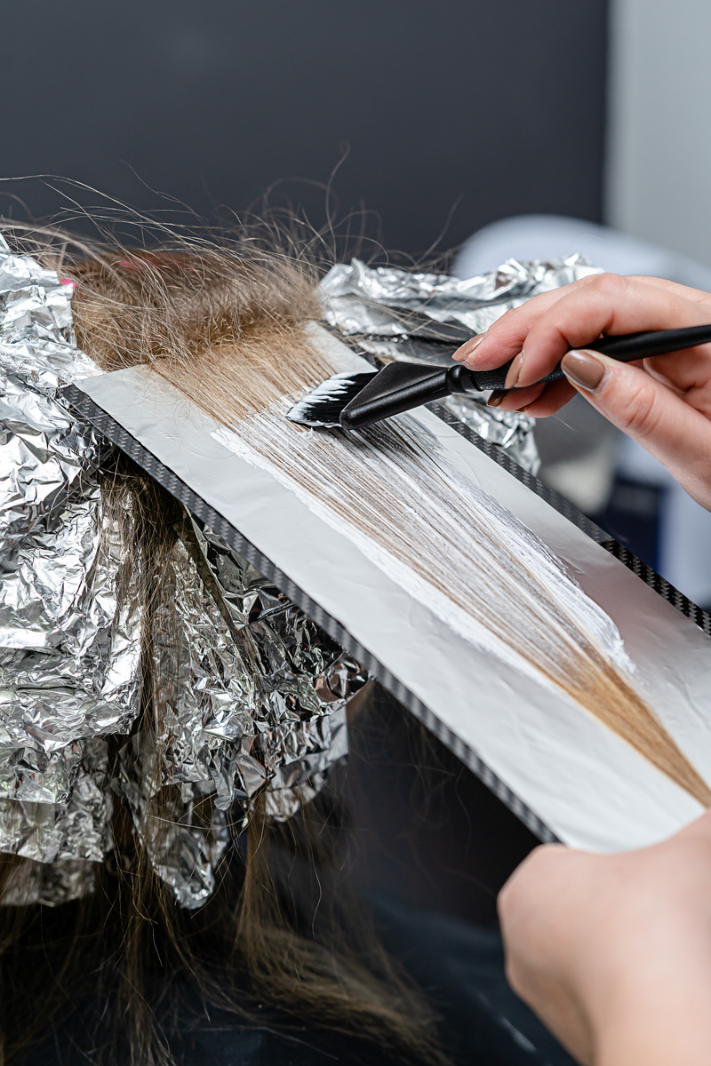 Hairstylist Applying Bleach on a Person's Hair with Foil